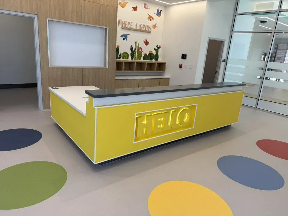 Commercial reception desk with illuminated HELLO signage and oak casework