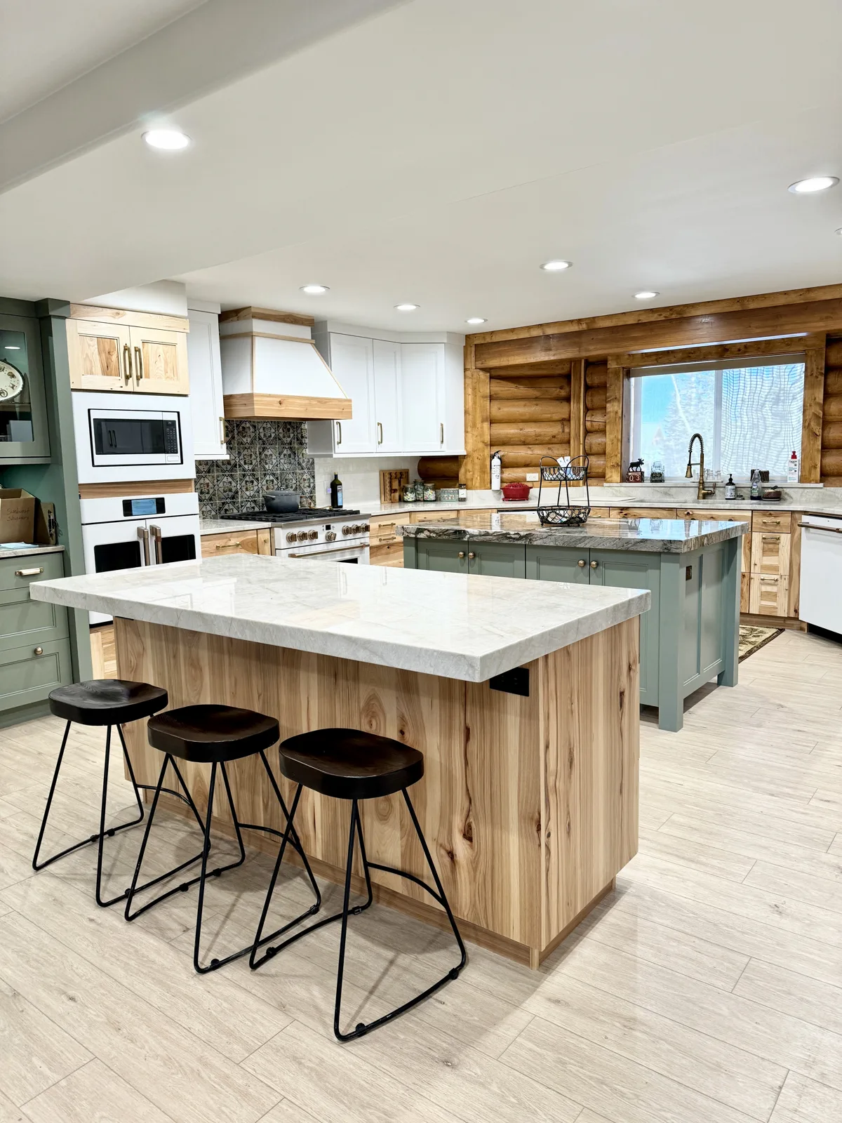 Green island kitchen with hickory cabinets and custom white range hood